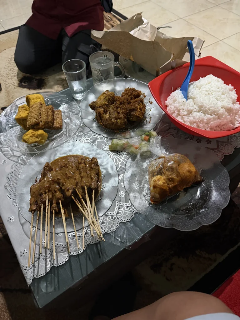 Borden met saté, rijst en gefrituurde hapjes op tafel